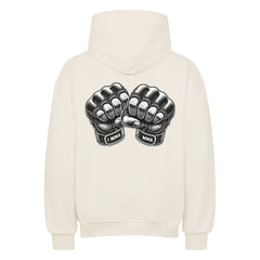 Der Oversized Hoodie "MMA" von MarketPrint ist cremefarben, mit einer Illustration von zwei schwarzen MMA-Handschuhen, die sich an den Knöcheln berühren, und "MMA" auf den Handgelenksbändern auf dem Rücken. Er hat eine Kapuze, lange Ärmel und einen hohen Tragekomfort.