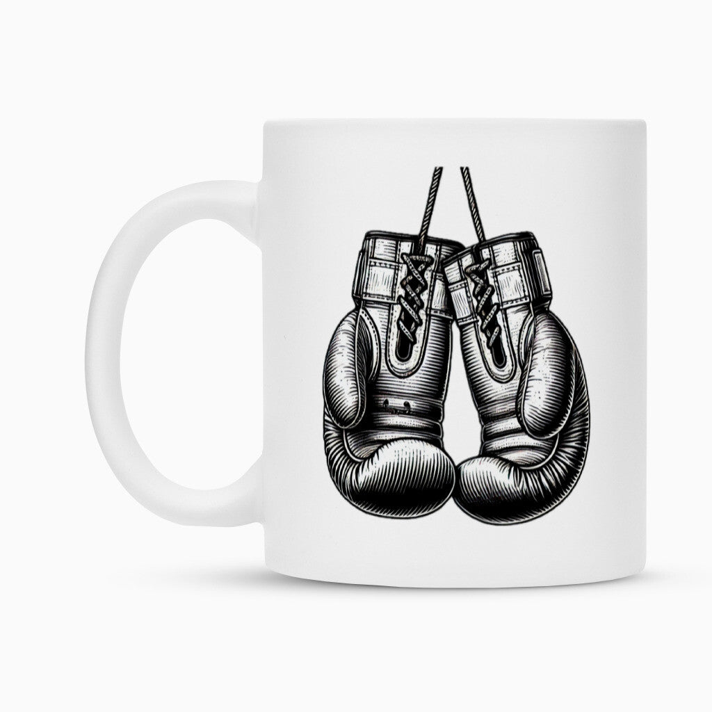 Die Tasse "Box-Handschuhe" von MarketPrint ist eine weiße Keramiktasse mit einer detaillierten Schwarz-Weiß-Skizze von zwei Boxhandschuhen. Sie verfügt über eine Duraglaze Beschichtung für dauerhafte Brillanz.