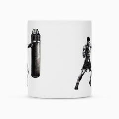 Die Tasse "Boxer" von MarketPrint ist eine weiße Keramiktasse, die einen schwarz-weißen Boxer in Kampfstellung gegenüber einem Boxsack zeigt, mit Abstand auf der Tasse und mit einer robusten Duraglaze-Beschichtung versehen.