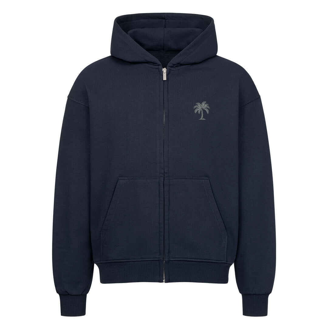 Der Infinity Merch Oversized Zipper Hoodie "Strand" in Marineblau verfügt über eine Kapuze, Vordertaschen und eine kleine Palmengrafik auf der linken Brust. Hergestellt aus 100% Baumwolle und auf einem einfarbig weißen Hintergrund abgebildet.