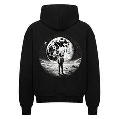 Der Oversized Zipper Hoodie "Astronaut" von Infinity Merch ist schwarz, besteht aus 100% Baumwolle und zeigt auf der Rückseite eine Grafik eines Astronauten auf dem Mond mit Sternen und Planeten im Hintergrund.