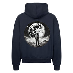 Der Oversized Zipper Hoodie "Astronaut" von Infinity Merch ist ein schwarzer Kapuzenpulli aus 100% Baumwolle in Oversized-Passform mit einer Rückengrafik eines Astronauten auf dem Mond mit großem Mond und Sternenhimmel.
