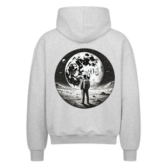 Der Oversized Zipper Hoodie "Astronaut" von Infinity Merch ist ein grauer Kapuzenpullover aus 100% Baumwolle mit einer Astronauten-Illustration auf dem Rücken, die auf einem felsigen Mond unter Sternen und Planeten steht.