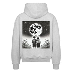 Der Oversized Zipper Hoodie Brüder-Mond von Infinity Merch zeigt einen schwarz-weißen Rückendruck von zwei Kindern im hohen Gras, die einen detaillierten Mond vor einem Sternenhimmel betrachten.